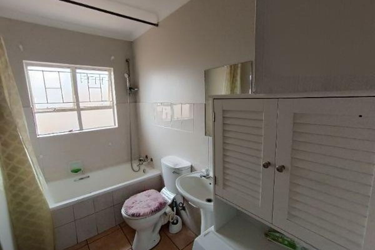 A functional bathroom featuring a bathtub with shower attachment, pedestal basin, toilet, and built-in storage cabinetry with tiled flooring.