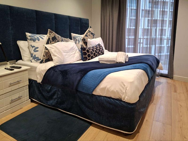 A well-maintained bedroom featuring light wood-look laminate flooring and a sliding glass door leading to an outdoor area.