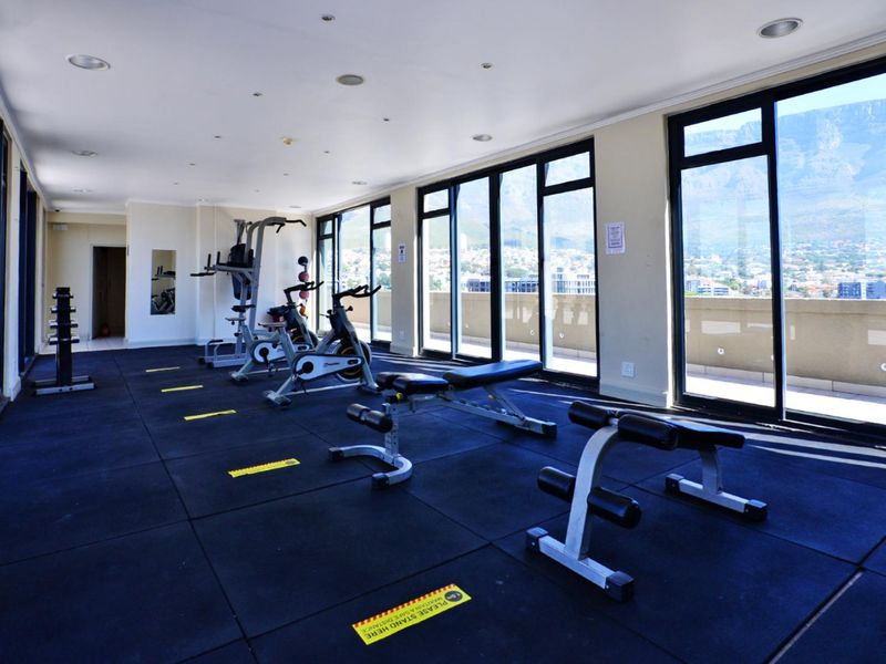 A well-lit, modern gym facility featuring rubber flooring, large sliding glass doors, and expansive views of the surrounding area.