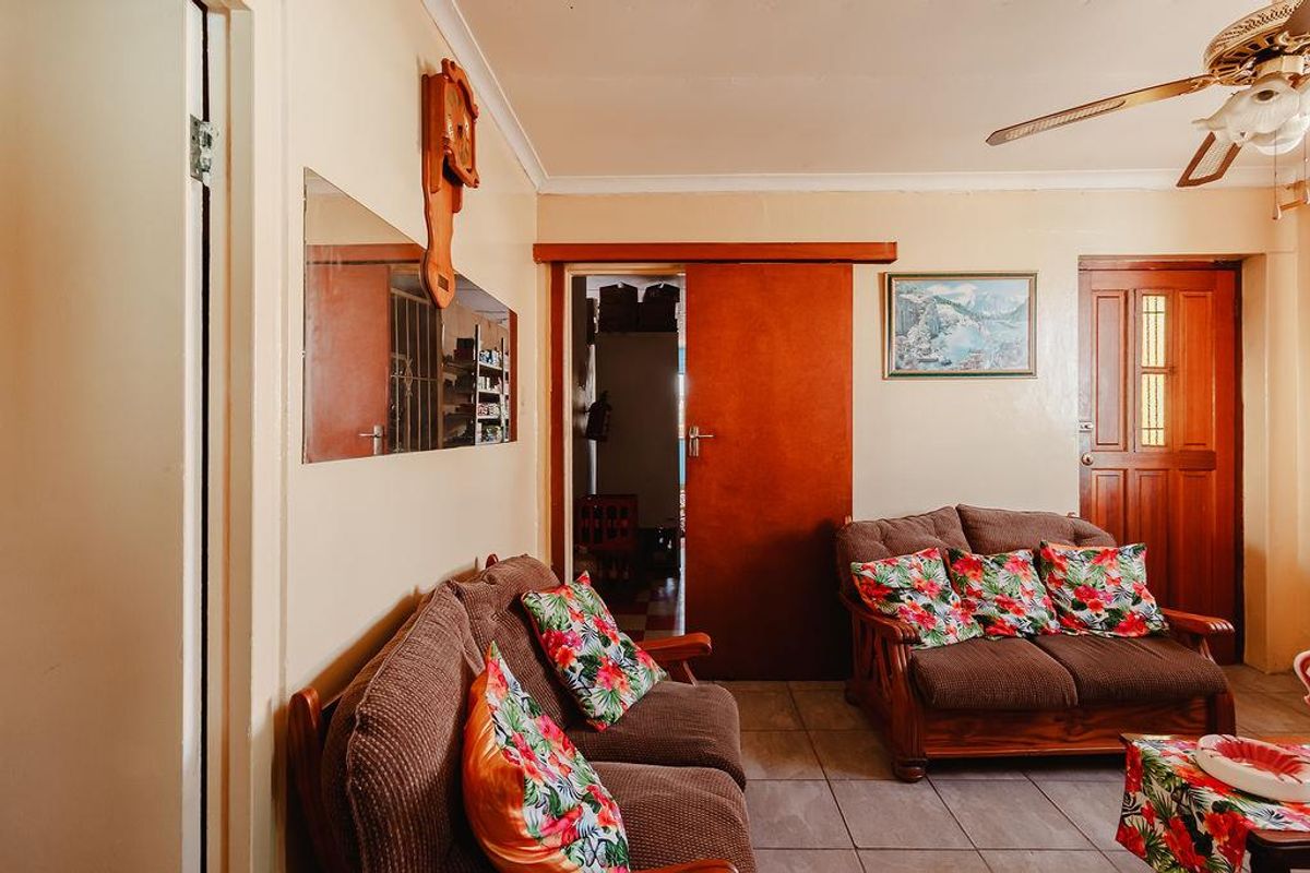 A living room featuring tiled flooring, a ceiling fan, and a sliding door, presenting a dated aesthetic with potential for modernization.