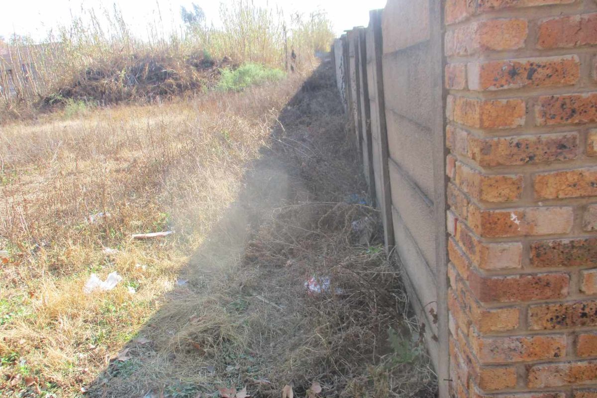 A view of the vacant residential land showing a precast concrete boundary wall and a face brick pillar along the property perimeter.