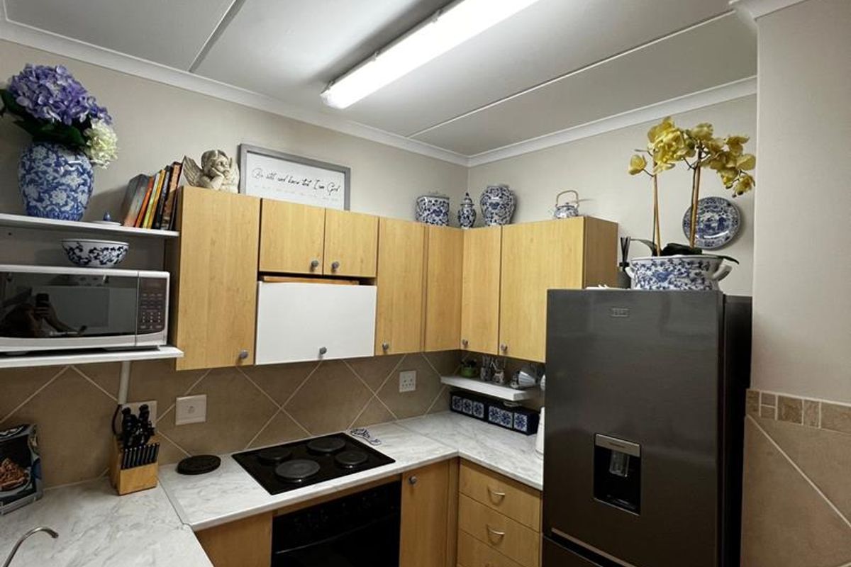 Compact kitchen featuring light wood cabinetry, laminate countertops, a built-in electric hob and oven, and a double stainless steel sink.