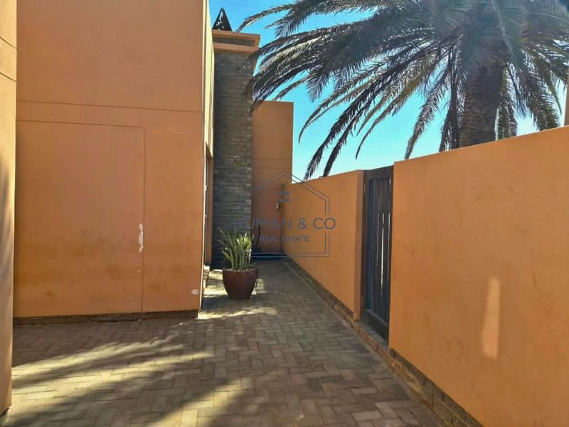 A paved rear courtyard area featuring a stone accent wall and perimeter boundary wall.