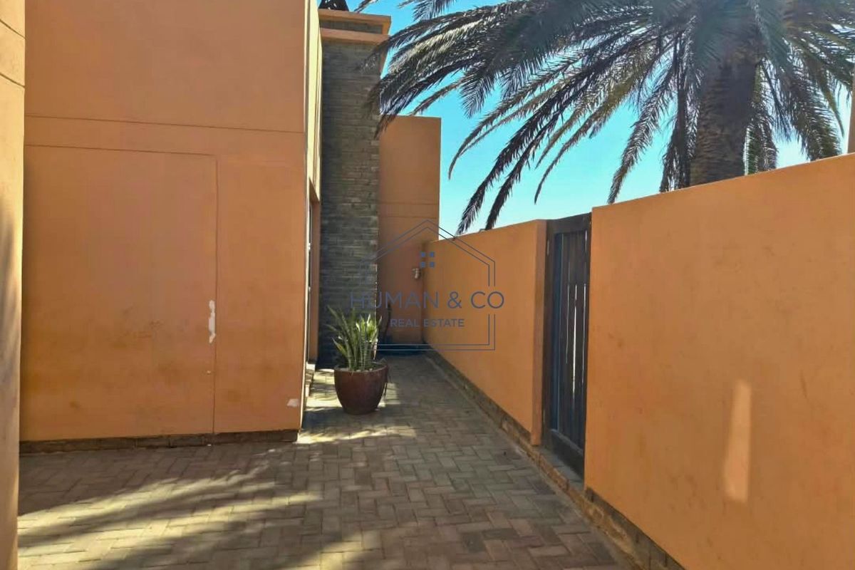 A paved rear courtyard area featuring a stone accent wall and perimeter boundary wall.