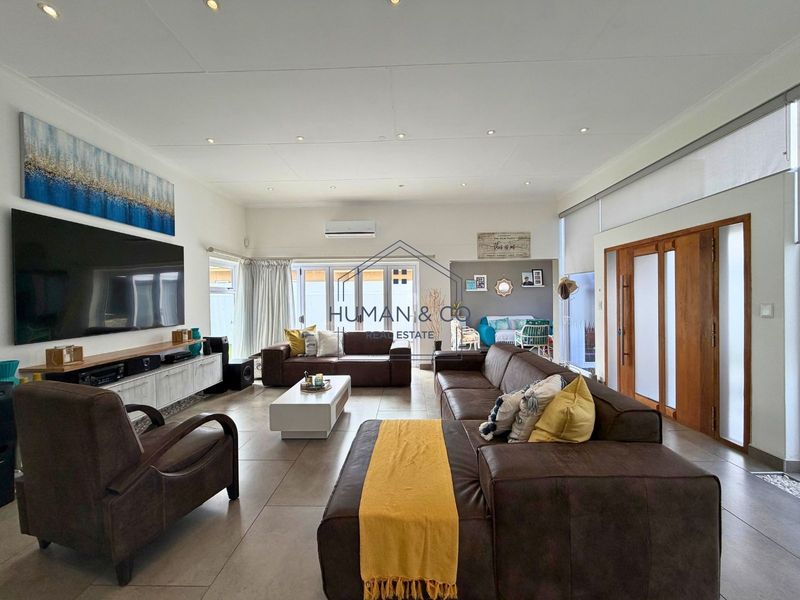 Spacious living room featuring tiled flooring, recessed lighting, a wall-mounted air conditioner, and large sliding glass doors providing access to the outdoor area.