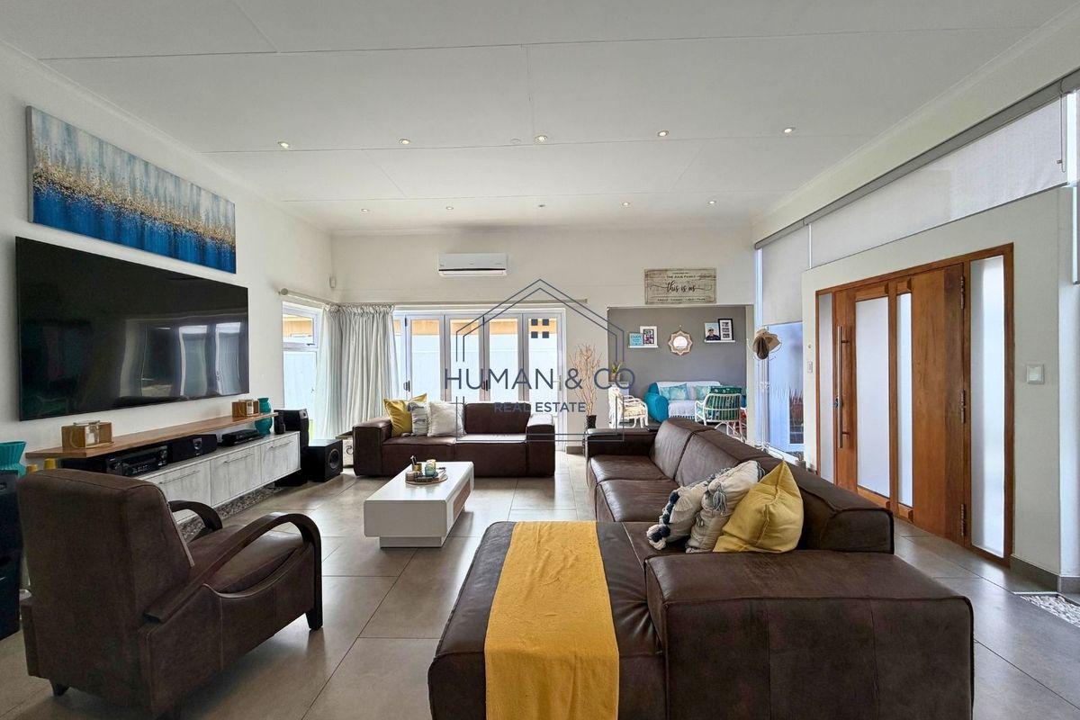 Spacious living room featuring tiled flooring, recessed lighting, a wall-mounted air conditioner, and large sliding glass doors providing access to the outdoor area.