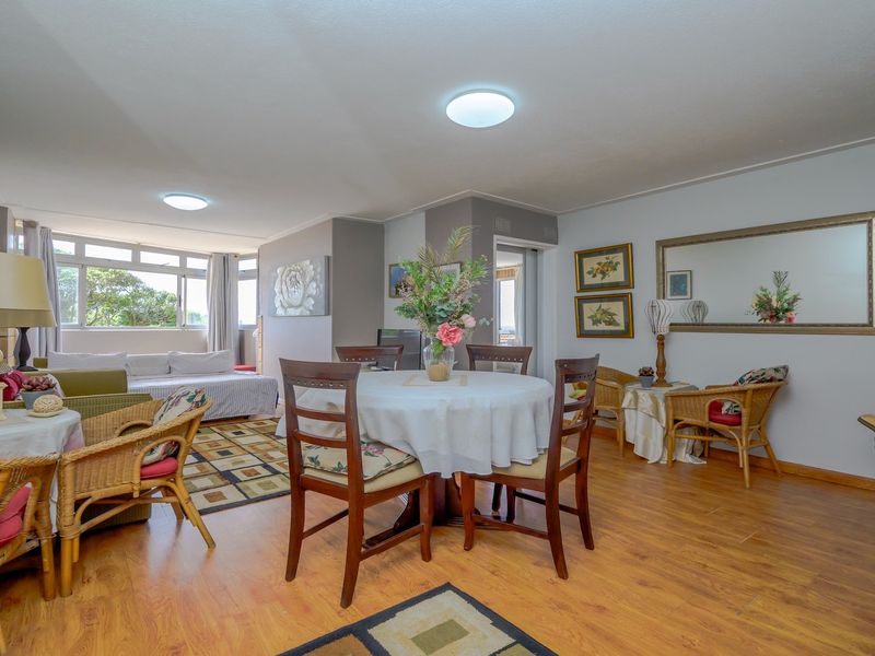 Spacious open-plan living and dining area featuring laminate flooring, ample natural light from large windows, and neutral wall finishes.
