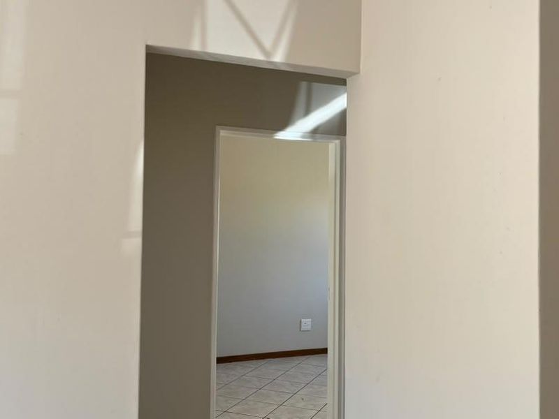 A view through a doorway into an adjacent room, featuring neutral wall finishes and tiled flooring throughout the transition space.