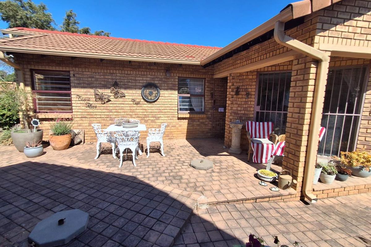 A paved rear patio area featuring facebrick walls, tiled roofing, and security bars on the windows, providing a functional outdoor living space.