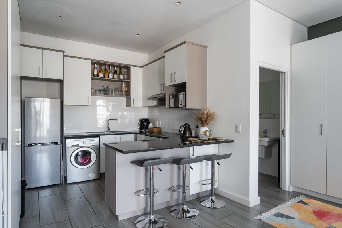 Modern kitchen featuring granite countertops, sleek cabinetry, integrated appliances, and a breakfast bar, seamlessly connected to the living area.
