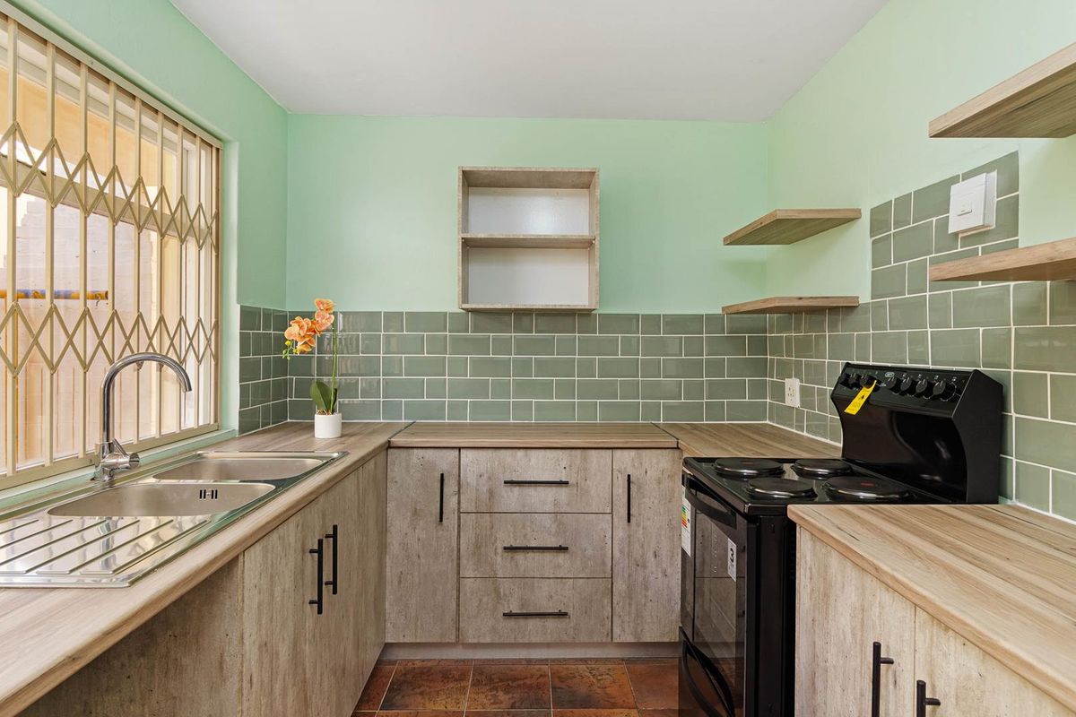 A clean, modern kitchen featuring light wood-finish cabinetry, subway tile backsplash, double basin sink, and a freestanding stove with ample counter space.