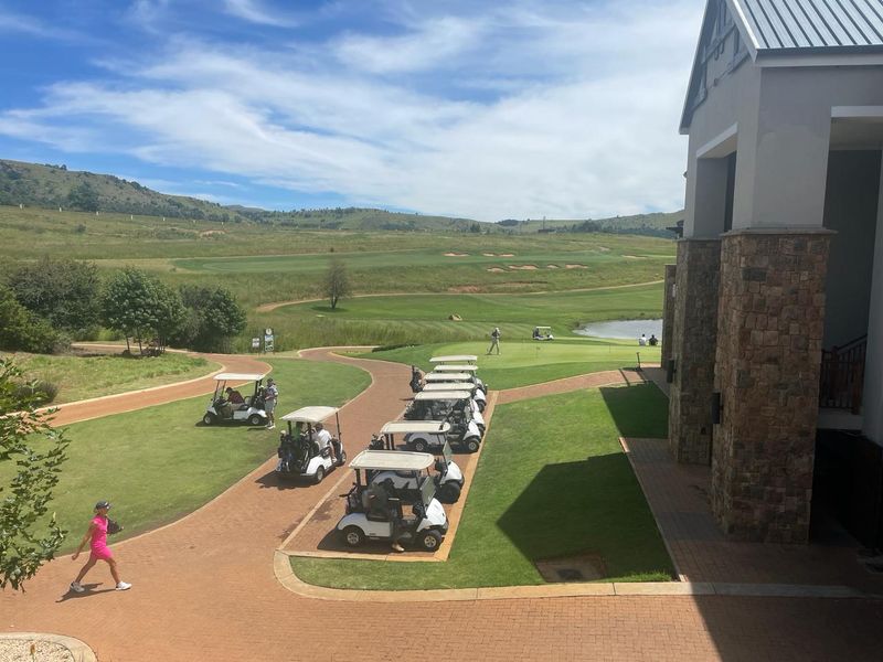 Scenic view overlooking a well-maintained golf course with stone-clad building architecture and paved pathways.