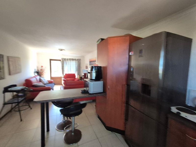 Open plan living area featuring tiled flooring and a kitchen with built-in cabinetry and a breakfast bar.