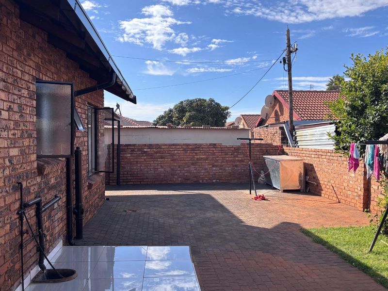 A private rear courtyard featuring face-brick walls, paved flooring, and a small garden area, providing a functional outdoor space.