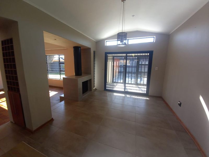 Spacious living area featuring tiled floors, a modern fireplace, vaulted ceilings, and large sliding doors leading to the exterior.