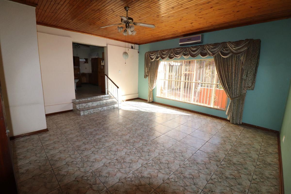 Spacious living area featuring tiled flooring, timber ceiling, and a split-system air conditioner, with a step leading to an adjacent room.