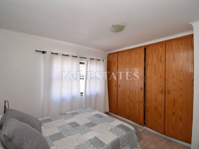 A bedroom featuring built-in wooden wardrobes and a window with curtain rod.