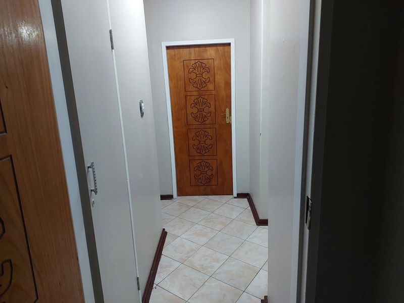 A functional interior hallway featuring tiled flooring and wooden doors with decorative paneling.