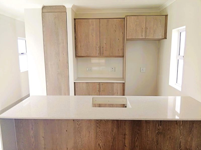 Modern kitchen featuring wood-grain cabinetry, stone countertops, and a tiled backsplash, offering a clean and functional space ready for final appliance installation.
