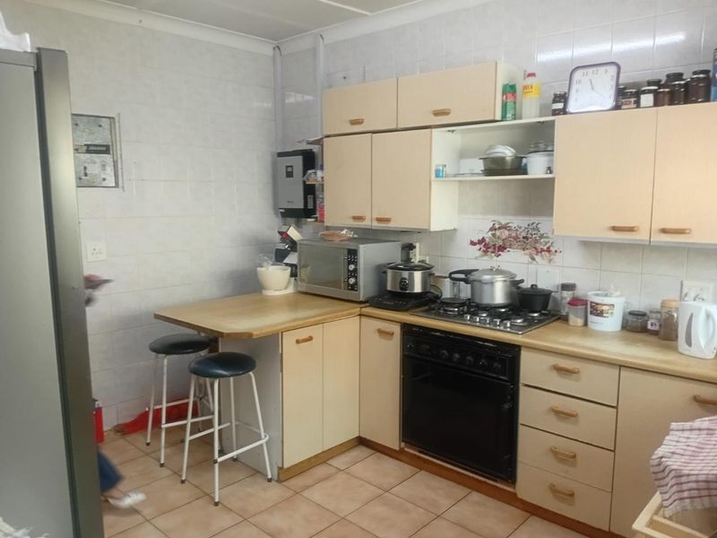 A functional kitchen featuring dated cabinetry, a gas hob, built-in oven, and tiled splashbacks, offering potential for a modern renovation.