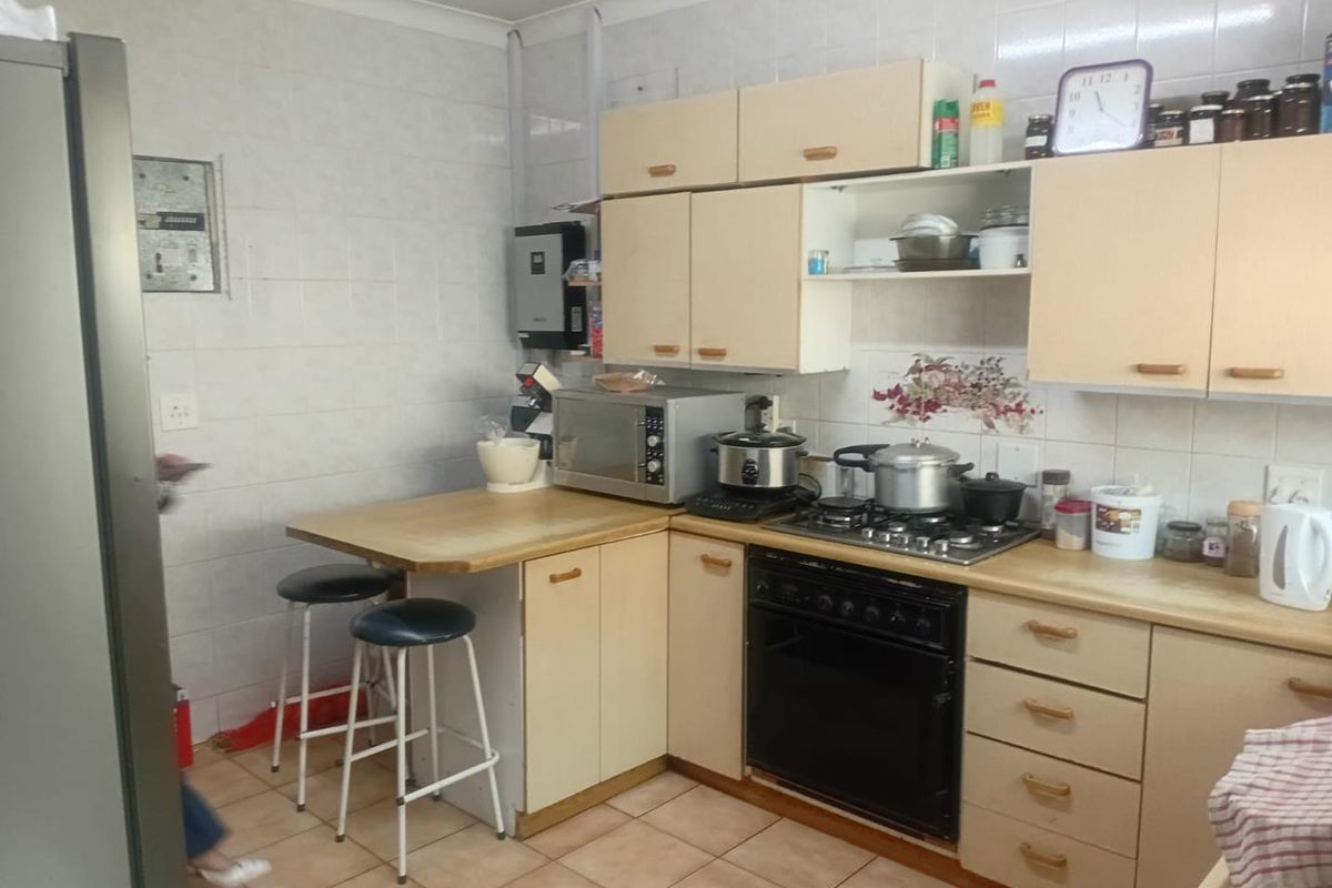 A functional kitchen featuring dated cabinetry, a gas hob, built-in oven, and tiled splashbacks, offering potential for a modern renovation.