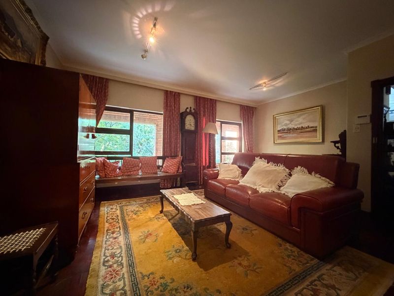 A cozy living room featuring warm parquet flooring, track lighting, and large windows that provide natural light.