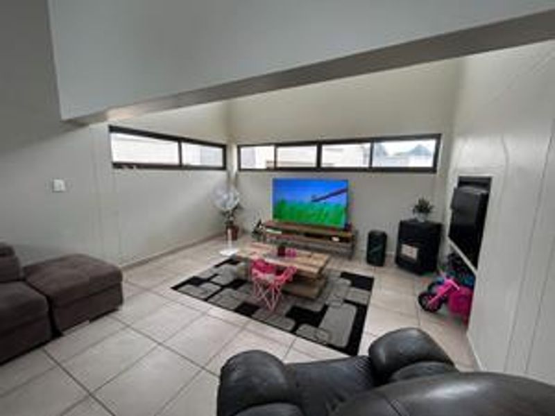 Spacious living room featuring high vaulted ceilings, clerestory windows for natural light, tiled flooring, and a built-in fireplace.