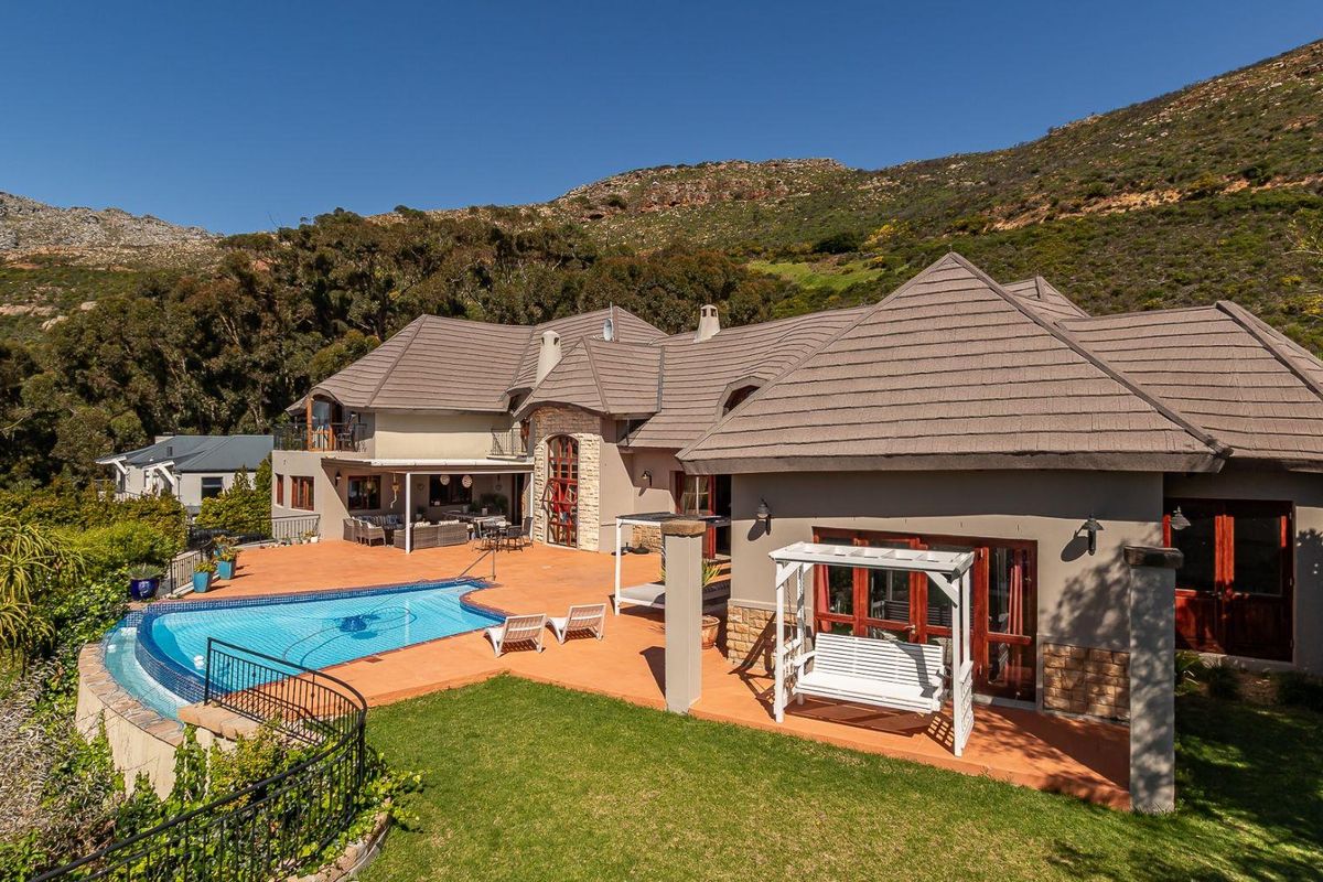 Spacious rear exterior featuring a swimming pool, expansive tiled patio area, and stone-accented facade set against a scenic mountain backdrop.