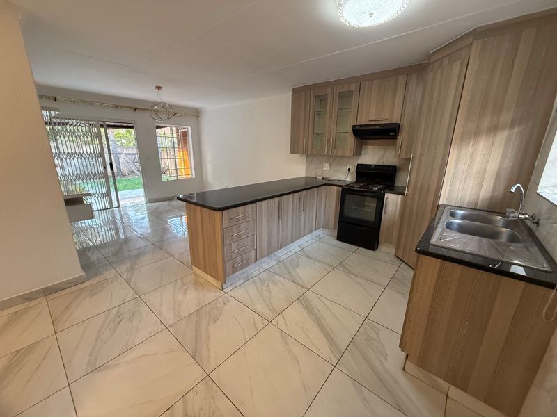 Spacious open-plan kitchen and living area featuring modern laminate cabinetry, granite countertops, and large-format porcelain floor tiles with direct access to the rear garden.