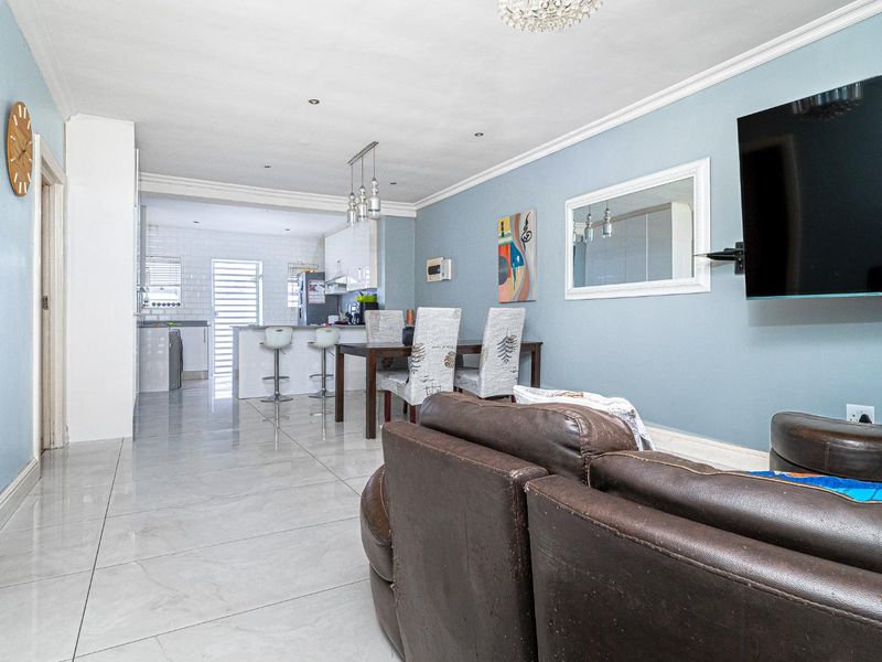 Open-plan living and dining area featuring polished porcelain floor tiles, recessed lighting, and a modern kitchen with a breakfast island.