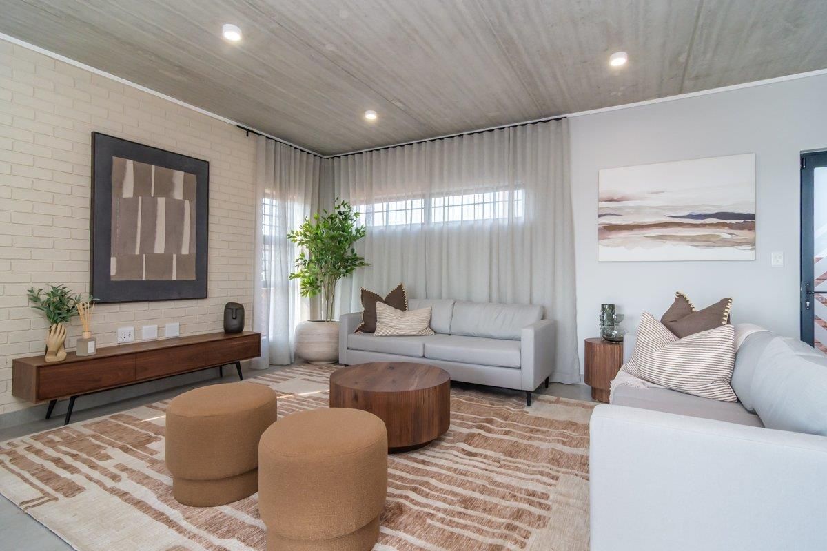 Modern living room featuring an exposed concrete ceiling, painted brick feature wall, and large windows with integrated curtain tracks.