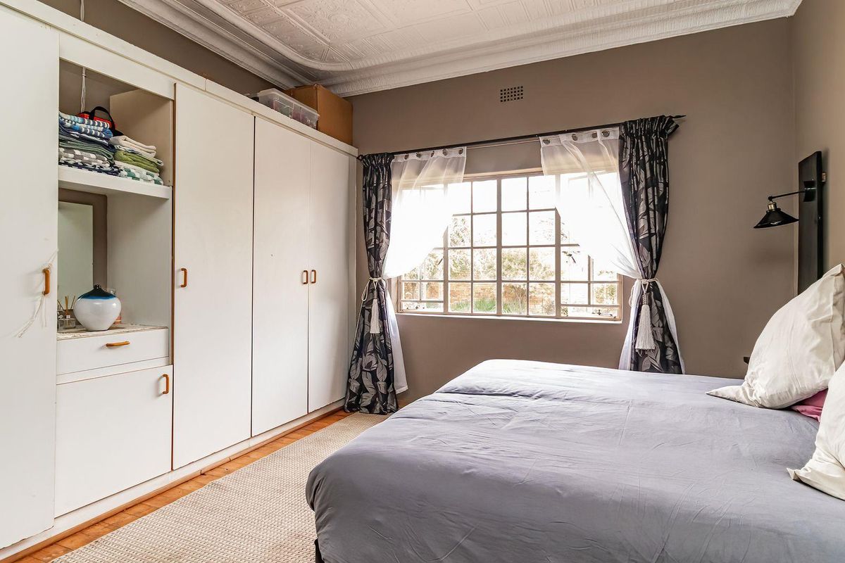 A bedroom featuring built-in white cabinetry, a multi-pane window, and decorative ceiling molding.