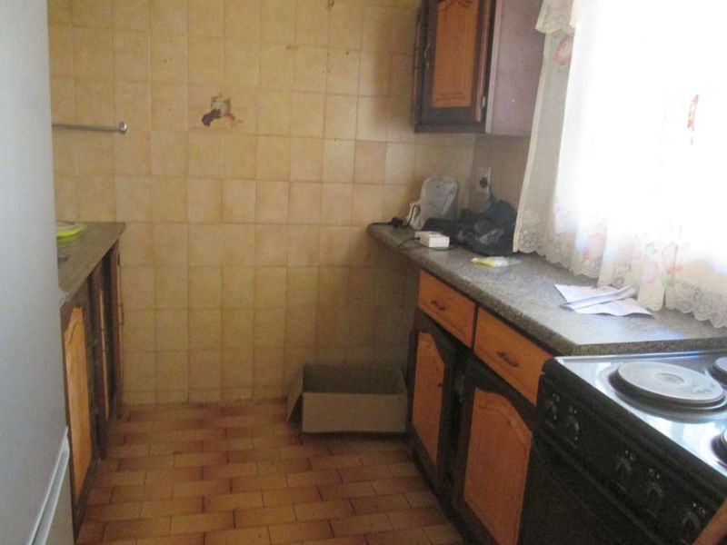 A dated kitchen featuring original cabinetry, stone countertops, and tiled finishes, offering significant potential for a modern renovation and layout update.