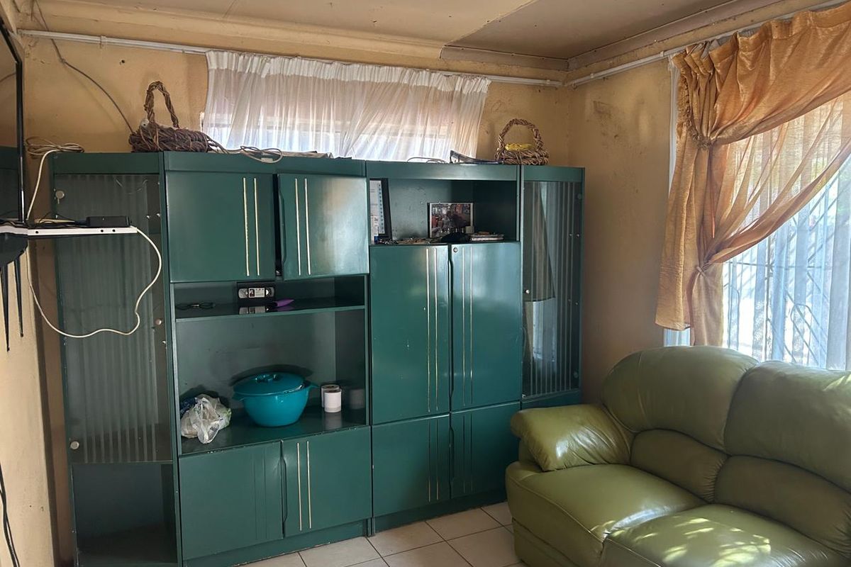 A living room space featuring tiled flooring and built-in cabinetry, requiring cosmetic updates and wall repairs to restore its condition.