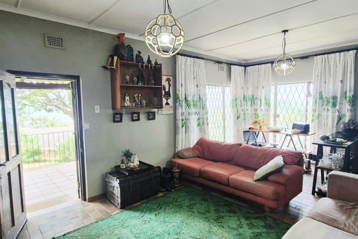 A living room featuring tiled floors, pendant lighting, and direct access to an outdoor patio area through a security door.
