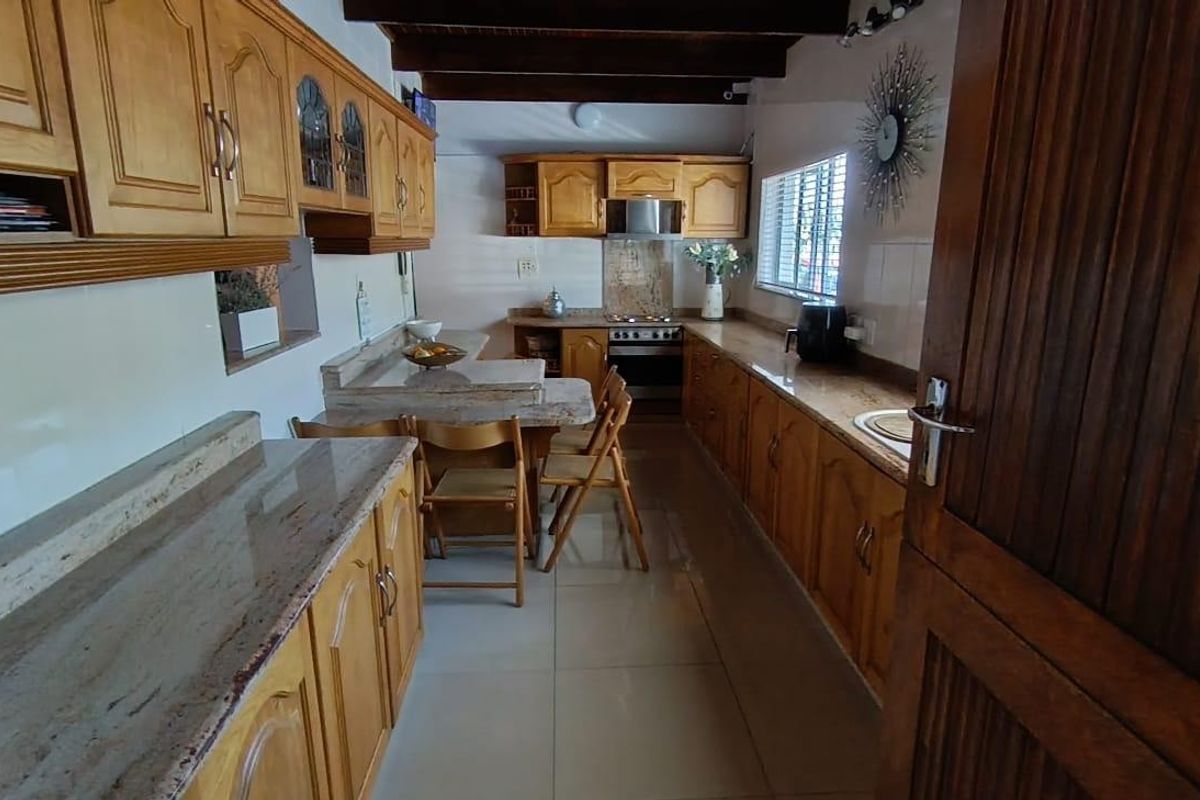A functional kitchen featuring warm wooden cabinetry, granite countertops, built-in appliances, and exposed timber ceiling beams, offering a classic and practical workspace.
