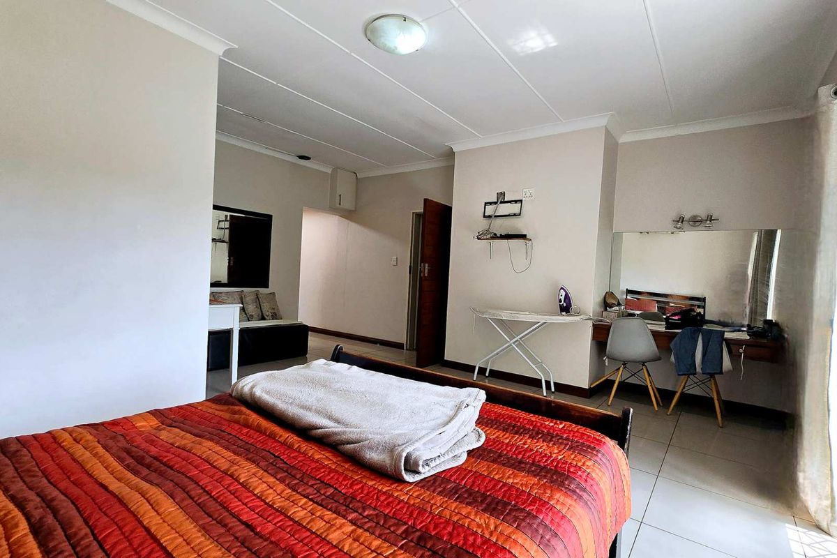 A bedroom featuring tiled flooring, built-in vanity area, and sliding door access to the exterior.