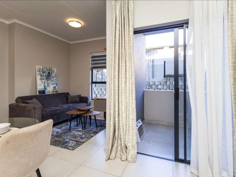 Open plan living area featuring neutral tiled flooring and a sliding glass door providing direct access to a private balcony.