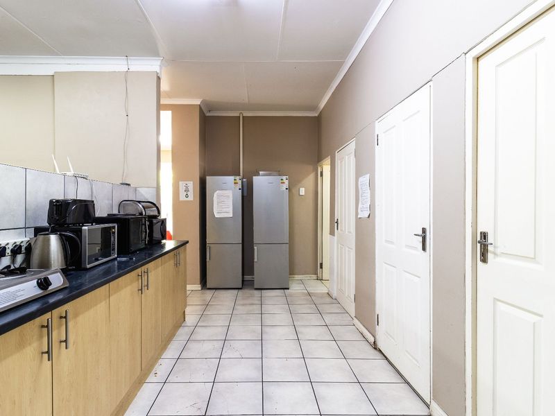 A functional scullery area featuring laminate cabinetry, dark countertops, tiled splashbacks, and tiled flooring, providing additional prep and storage space.