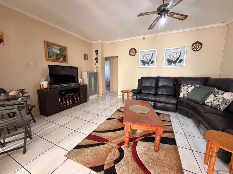 A spacious living room featuring neutral walls, ceramic floor tiles, and a ceiling fan, providing a comfortable and functional living area.
