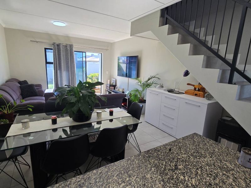 Open plan living and dining area featuring tiled floors, a modern staircase, and direct access to the outdoor patio through sliding glass doors.