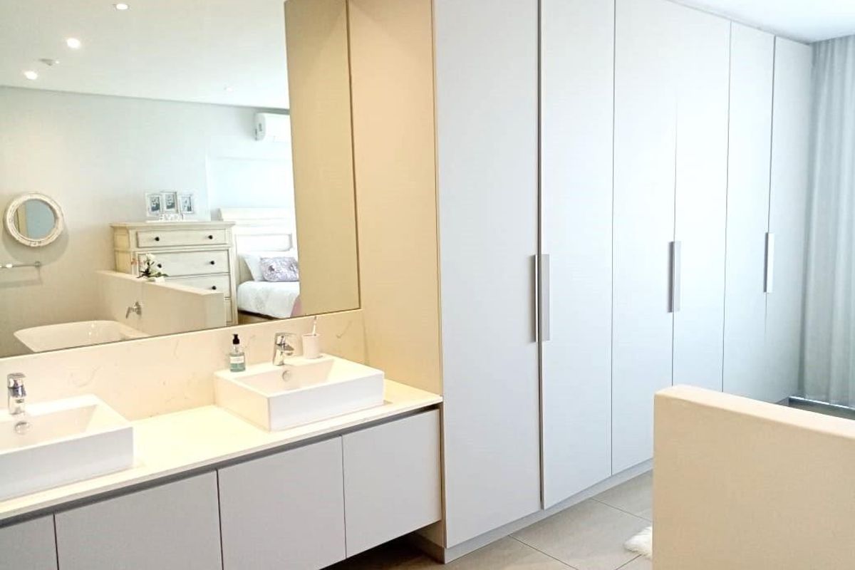 Modern bathroom featuring a double vanity with vessel sinks, a large wall mirror, and extensive built-in floor-to-ceiling cabinetry for ample storage.