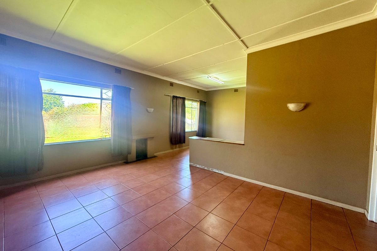 An empty living room featuring tiled flooring, wall sconces, and a partition wall, offering a blank canvas for potential renovation and interior design updates.