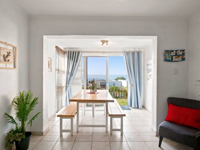 A bright dining area featuring ceramic floor tiles and a large sliding glass door that opens to an outdoor view.