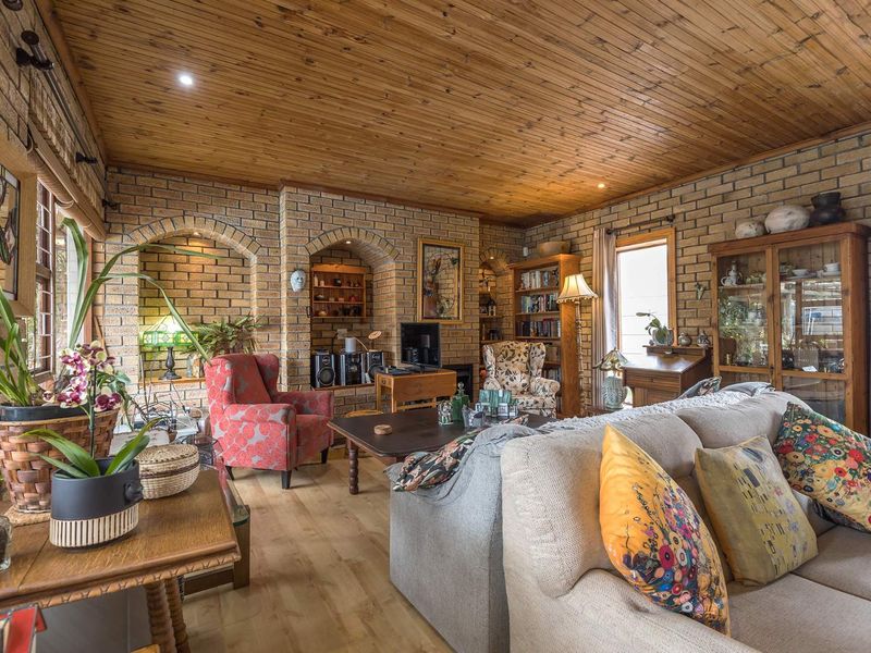 A cozy living room featuring exposed brick walls, a warm timber-paneled ceiling, and built-in arched wall niches, creating a rustic and character-filled atmosphere.