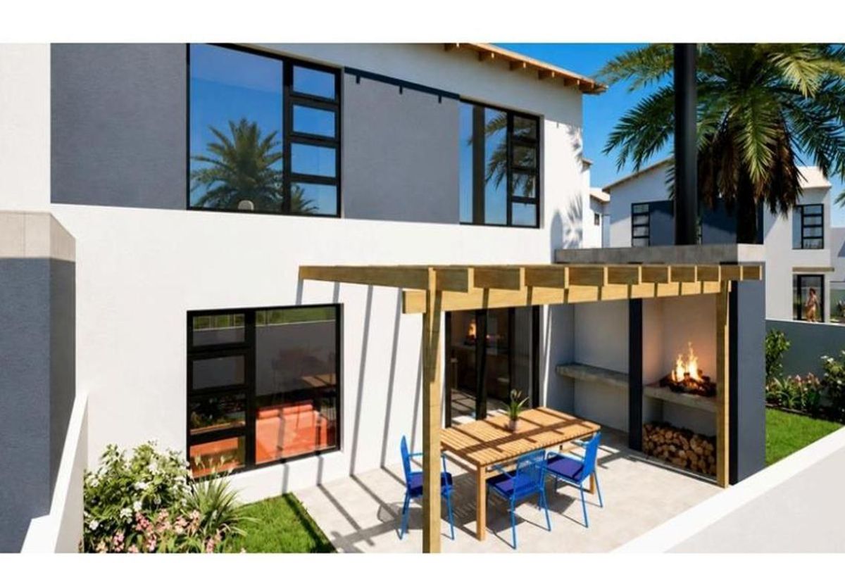 Rear exterior view of a modern townhouse featuring a paved patio, timber pergola, and a built-in outdoor braai area.