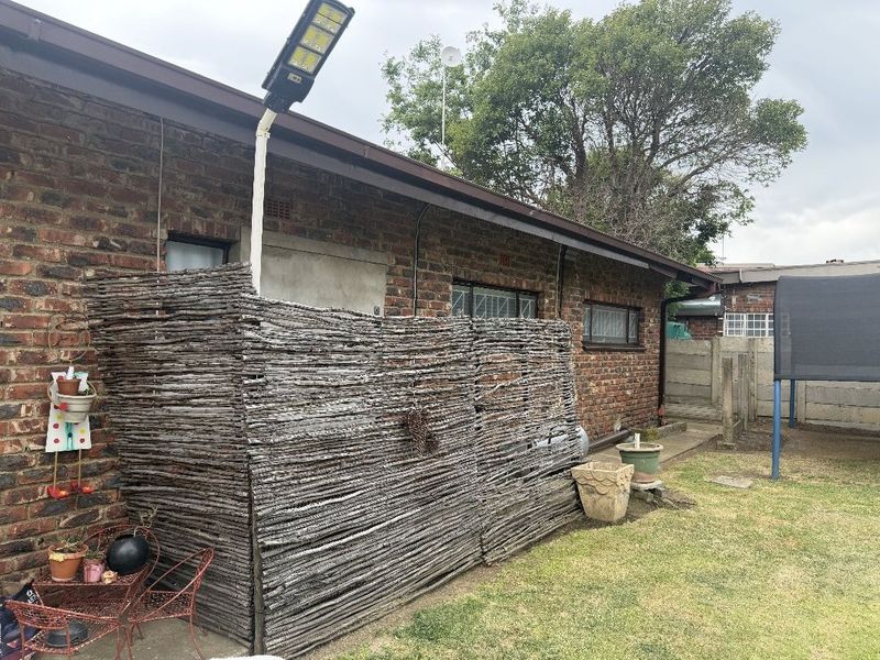 Rear exterior view of the property featuring a brick facade, concrete pathway, and a solar-powered light fixture.