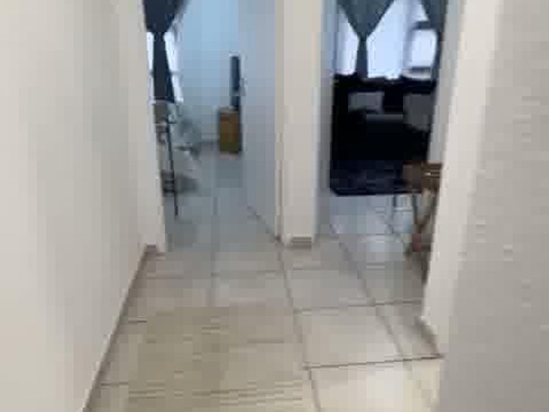 A tiled hallway providing access to two adjacent rooms, featuring neutral wall finishes and standard internal door frames.
