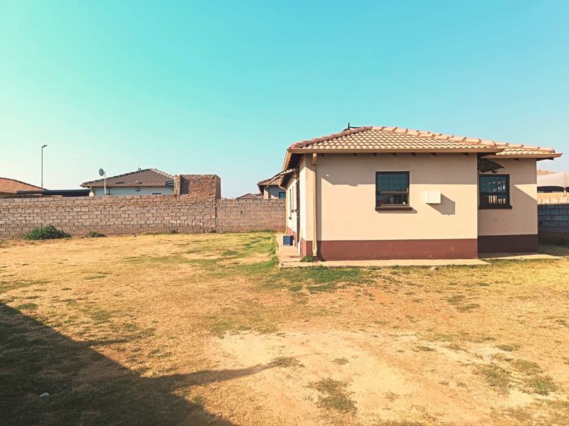 Rear view of the property featuring a large open yard, concrete tiled roof, and perimeter brick walling.