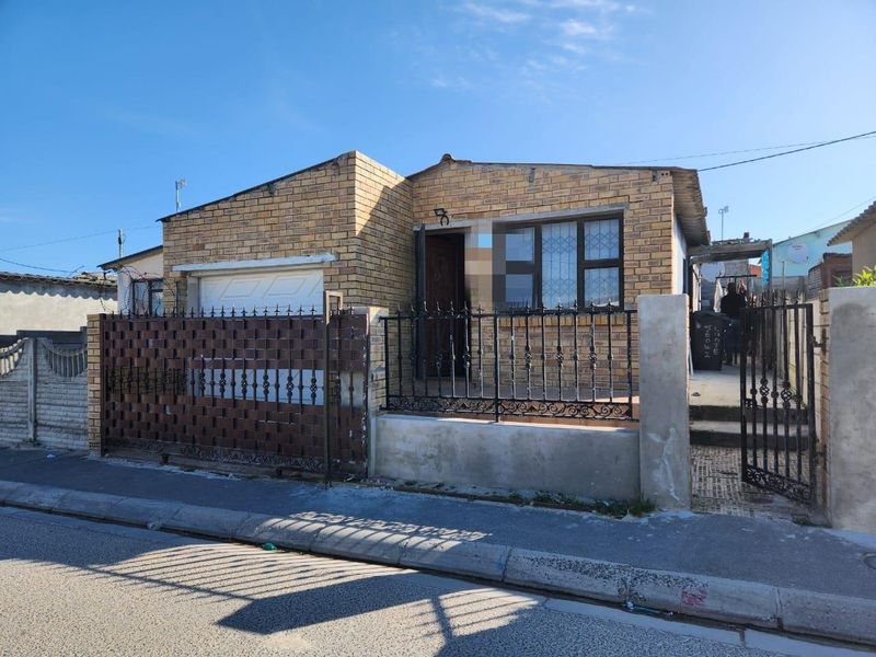 Front elevation of a face brick house featuring a single garage, secure wrought iron perimeter fencing, and security bars on the windows.